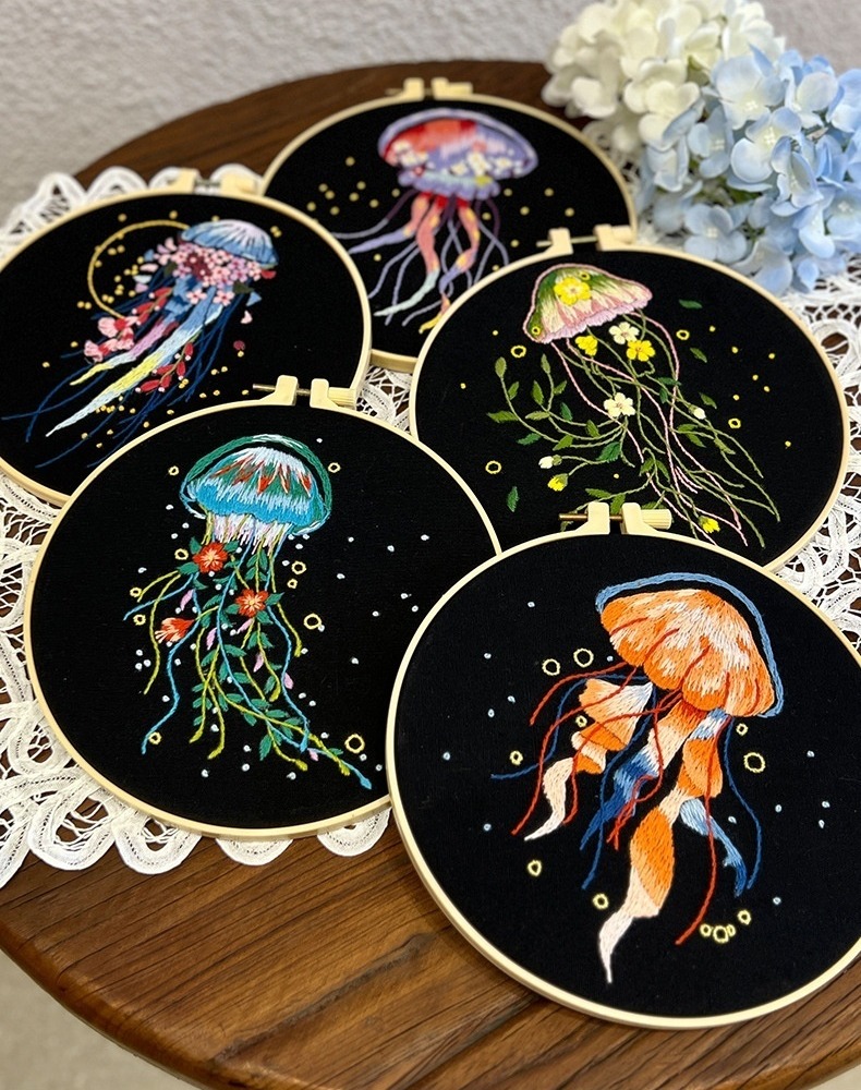 Five jellyfish embroidery designs on black fabric